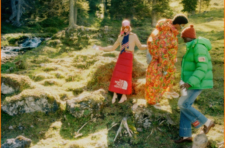 Three people dressed in The North Face x Gucci on a grassy hill.